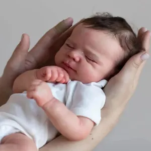 Lifelike 50cm newborn reborn doll in white bodysuit being gently held by hands