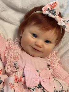 Detailed close-up of 50cm Reborn Maddie baby doll with red hair and blue eyes on plush rug