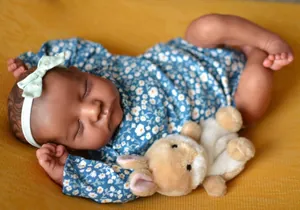 Detailed close-up of dark skin reborn baby Levi in blue floral romper with plush lamb