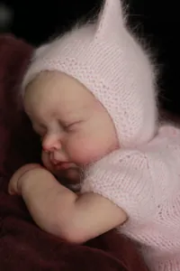 Gros plan d'une poupée reborn endormie avec peau 3D et tenue en tricot de mohair rose