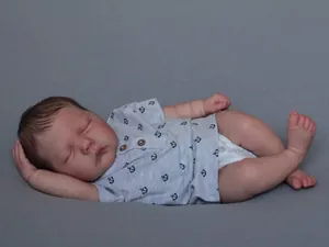 Macro shot of realistic reborn baby doll sleeping in anchor print outfit and diaper