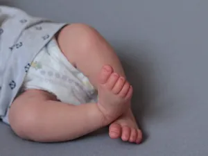 Detail shot of a 49cm newborn baby doll feet with anchor pattern onesie and white diaper