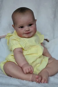 Realistische 60cm Reborn Puppe Maddie im gelben Kleid auf weißem Plüschteppich