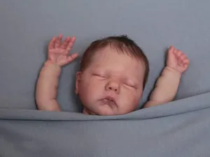 Close-up of lifelike newborn reborn doll with detailed skin texture and rooted hair