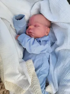 Close-up of a 19-inch sleeping reborn baby doll in a soft blue knitted bodysuit