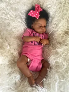 Détail d'une poupée reborn à la peau foncée, cheveux bouclés et tenue rose adorable