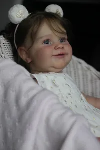 Gros plan d'une poupée reborn de 60cm avec bandeau ours et broderies dorées fines