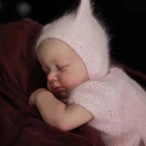 Poupée Reborn réaliste Loulou Awake de 49cm en tenue rose sur fond de velours rouge