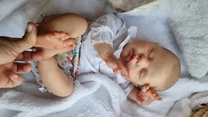 Detail of 22-inch reborn baby doll with 3D skin texture and veins sleeping on plush rug