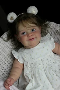 Gros plan d'une poupée reborn réaliste Maddie 60cm avec cheveux bouclés et robe à fleurs
