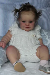 Detailed view of Maddie reborn baby doll in white lace romper and silver shoes