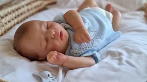Close-up of a 16 inch reborn baby doll featuring realistic skin texture and blue knitwear