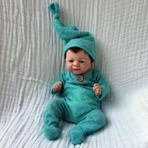 Realistic 46cm reborn baby doll in teal knit romper and knotted hat on white fabric