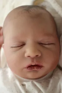 Close-up of reborn baby doll face with realistic skin texture and closed eyes sleeping