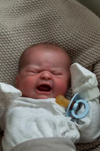 Close-up of lifelike newborn baby reborn doll crying face with pacifier accessory
