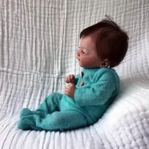 Realistic 46cm reborn baby doll in light blue knit jumper on white background