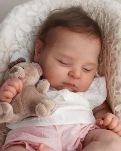 Gros plan d'une poupée reborn endormie avec peau 3D tenant un petit ours en peluche