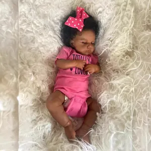 Poupée bébé reborn africaine 49cm en barboteuse rose sur fond de peluche blanche