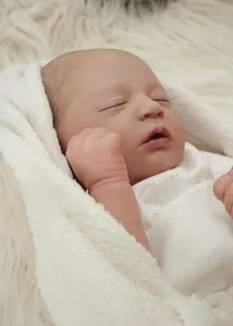 Close-up of sleeping 19-inch reborn baby doll with realistic skin texture on plush blanket