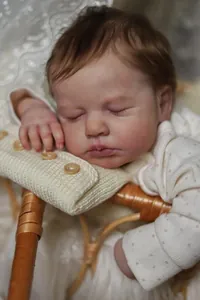 Close-up of sleeping Reborn LouLou baby doll with realistic skin texture and knitted pillow