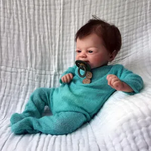 Realistic 46cm reborn baby doll with blue eyes and knit outfit on white textured background
