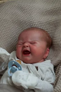 Detailed macro shot of crying reborn baby doll with realistic skin texture and hair