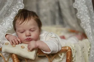 Detailed close-up of sleeping reborn baby doll with realistic skin and brown hair