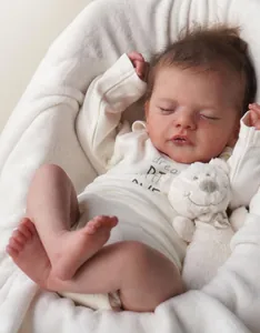 Detailed view of an 18-inch sleeping reborn baby doll with a white bear plush toy