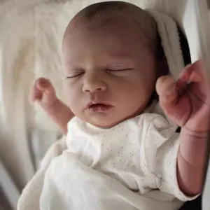 Lifelike 19-inch reborn sleeping baby doll in white polka dot outfit and soft wrap