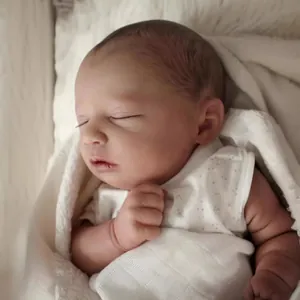 Realistic 19-inch sleeping reborn baby doll in white floral outfit with plush blanket