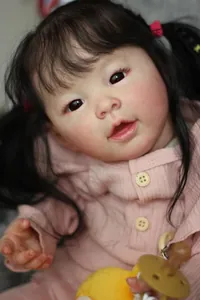 Close-up of lifelike 60cm reborn baby doll with black pigtails and pink waffle outfit