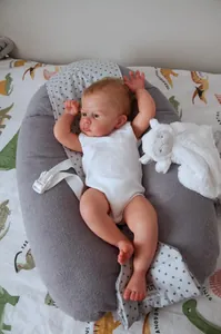 Realistic baby doll resting in a gray cotton nursing pillow with star print insert