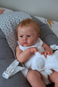 Close-up of a lifelike 24-inch reborn baby doll holding a soft plush white lamb toy