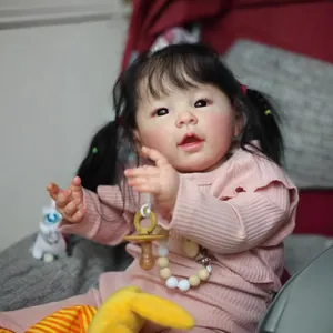 Realistic 60cm girl reborn doll with curly black pigtails in pink ribbed romper and plush toy