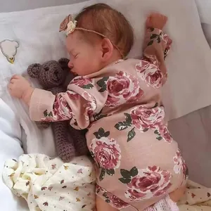 Poupée Reborn Rosalie 49cm en barboteuse rose à fleurs avec bandeau sur oreiller
