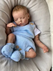 Detailed close-up of reborn baby doll in blue knit outfit with handmade wood buttons