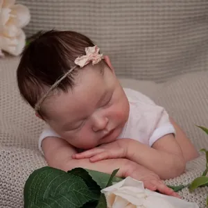 Detailaufnahme der schlafenden Puppe Laura auf beigefarbener Decke mit rosa Blumen