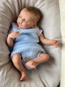Detailed close-up of reborn baby doll in blue knit outfit sleeping on waffle fabric