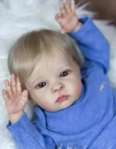 Close-up of 55cm realistic reborn baby doll with blonde hair in blue knit top