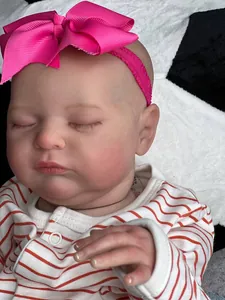 Close-up of 20-inch reborn doll with realistic 3D skin, red bow, and striped baby outfit