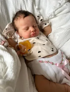 Gros plan d'une poupée reborn de 19 pouces endormie avec tétine sur tissu en coton