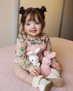 Detailed view of reborn baby doll in pink overalls holding plush rabbit toys