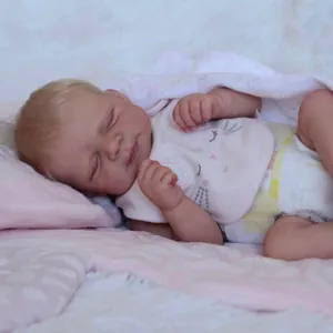 Close-up of sleeping reborn baby doll with detailed skin texture and pink embroidered bib