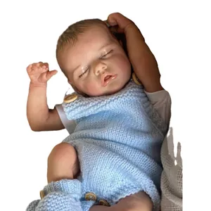 Lifelike 48cm Reborn Twin B baby doll sleeping in a blue knitted romper on white background
