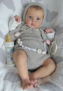Détail d'une poupée reborn en tenue grise tricotée avec attache-tétine à perles