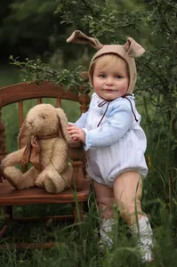 Close-up of 55cm realistic reborn baby doll Zoe in blue striped romper and bunny hat