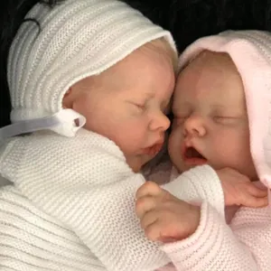 Close-up of Twin A and B newborn reborn dolls in white and pink knitted outfits