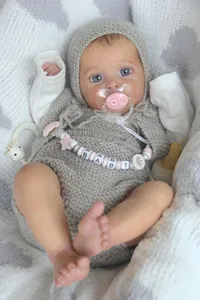 Détail de la poupée réaliste avec vêtements en tricot et chaîne de sucette rose