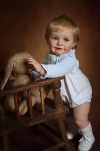 Detailed view of 55cm realistic reborn baby doll Zoe wearing blue striped romper and white shoes