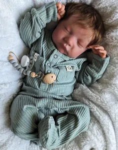 Vue détaillée de la poupée Reborn Levi endormie en tenue verte sur un tapis en peluche